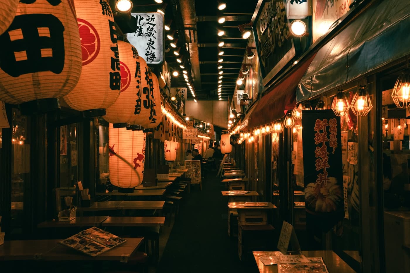 A narrow izakaya lane at night, lit by paper lanterns