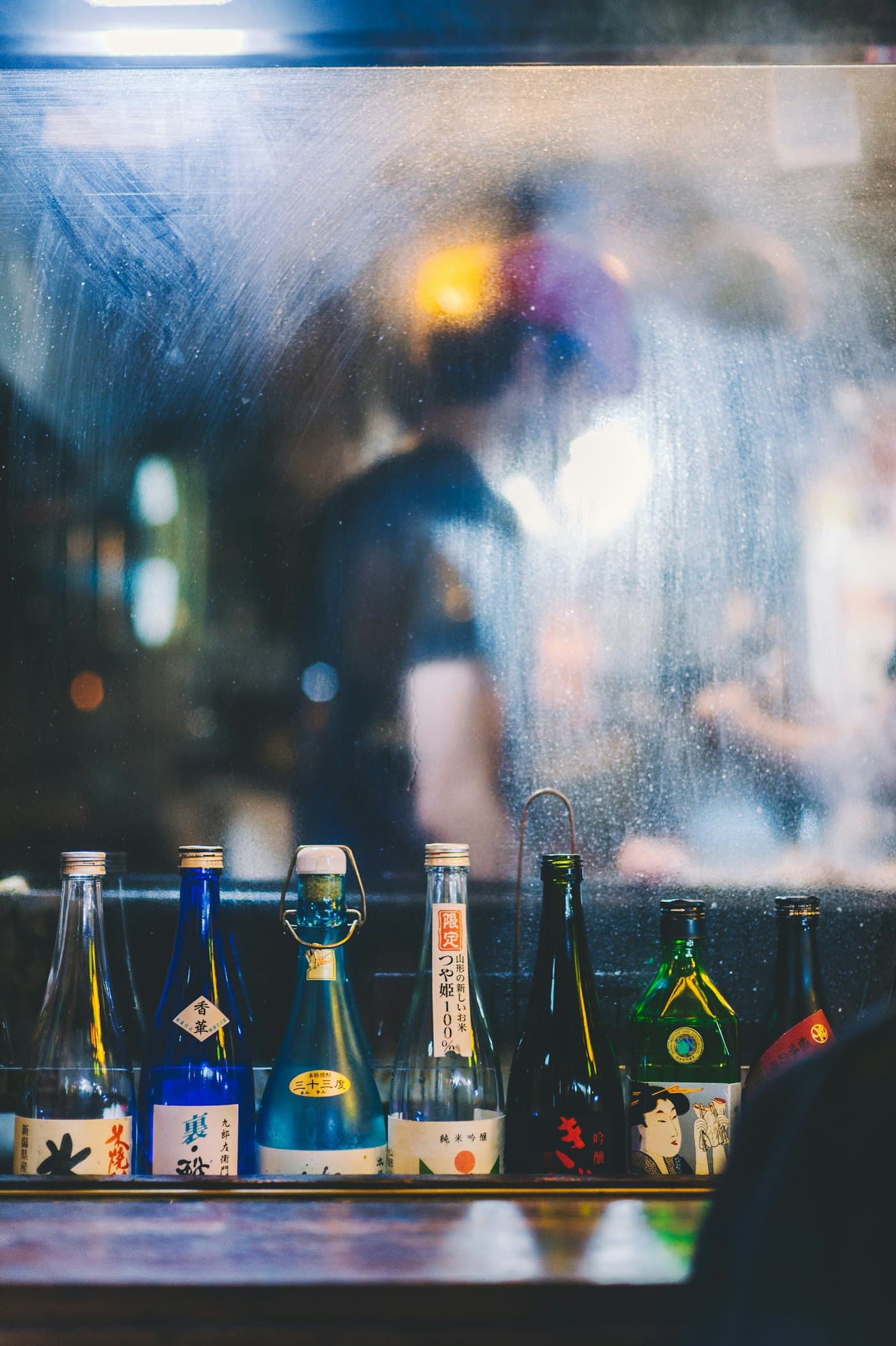 Sake bottles lined up on the counter of a Japanese izakaya