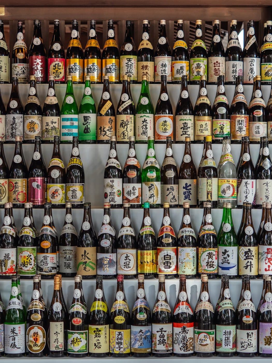 A shop wall stacked with Japanese sake bottles in their brewery labels