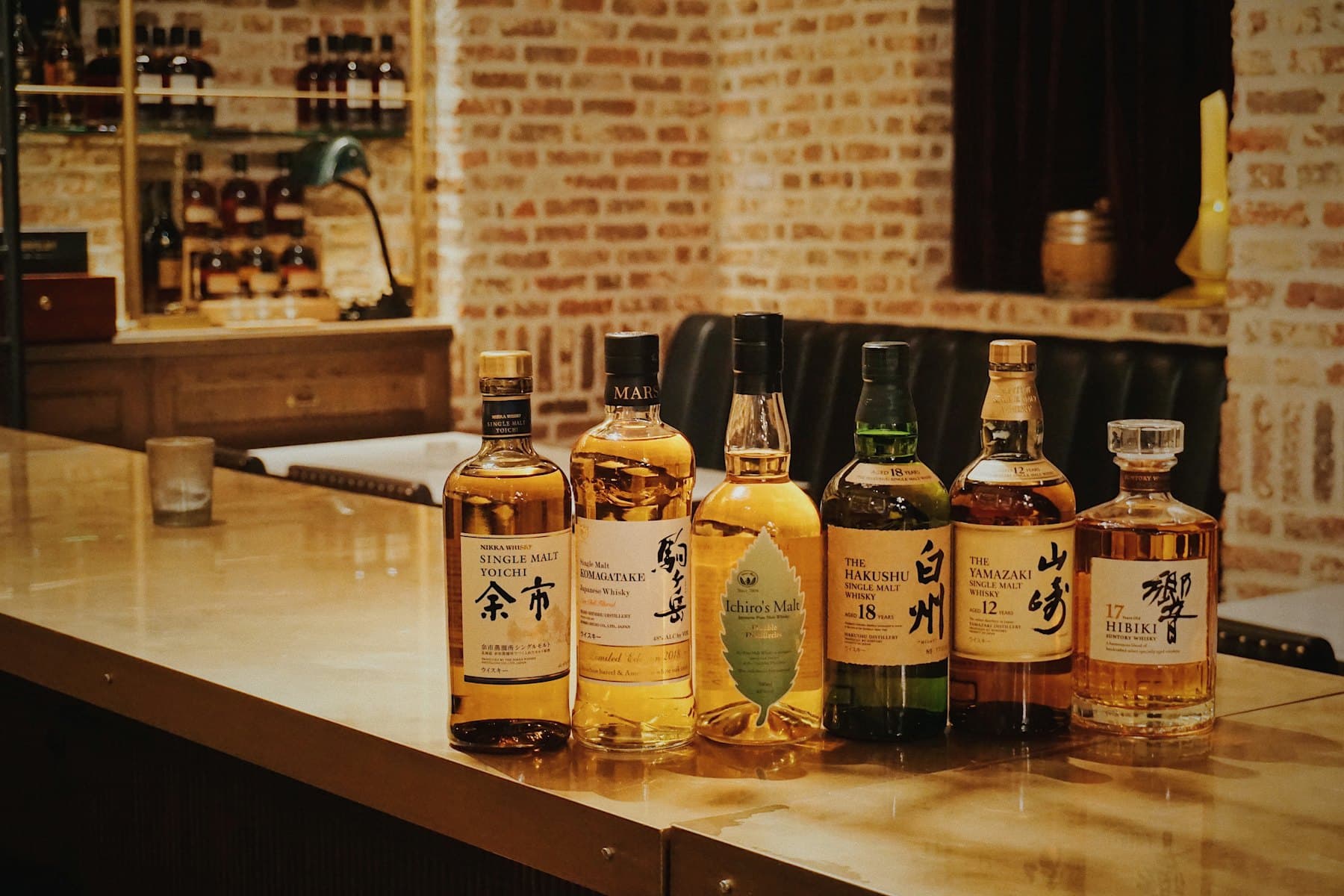 Japanese single malt and blended whisky bottles lined up on a bar counter